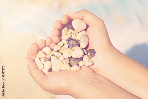 Close-up shot of hands with stones on a pebble beach background. Concept of summer holidays at sea, Zakynthos Island, Greece.