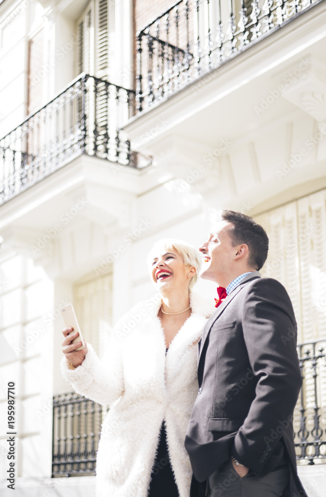 Man and woman with umbrella texting on smartphone