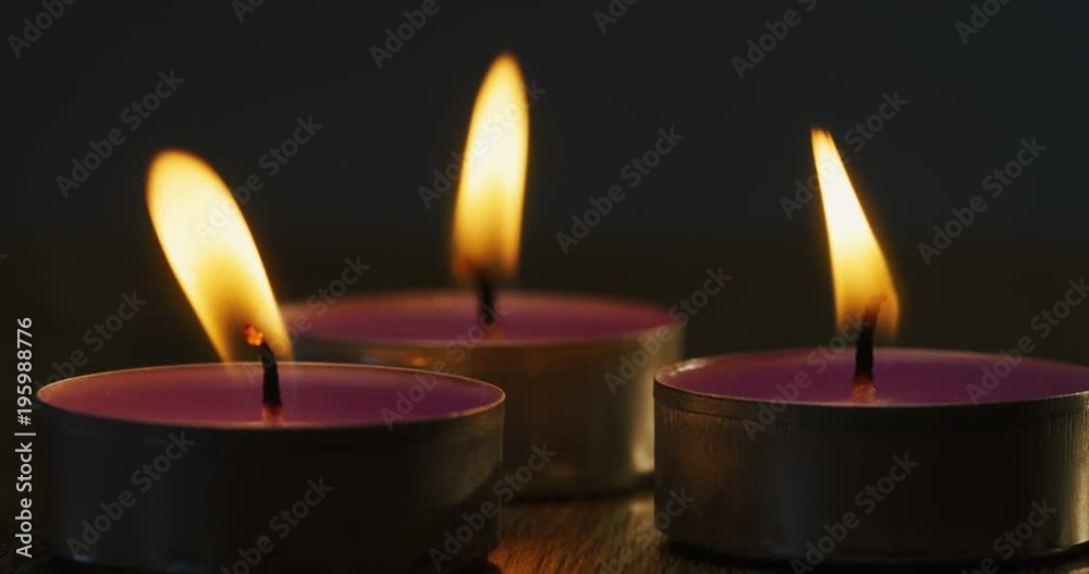 Close up of the three candles burning on the wooden table at night. Macro shoot Close up of the three candles burning on the wooden table at night. Macro shoot