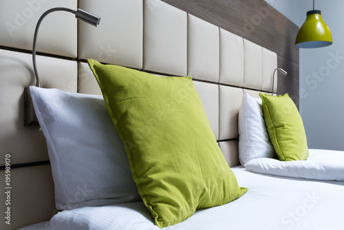 Canvas Print Green pillow, reading lamps and leather bed headboard in modern bedroom