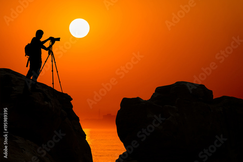 silhouette of photographer on top of mountain at sunset background