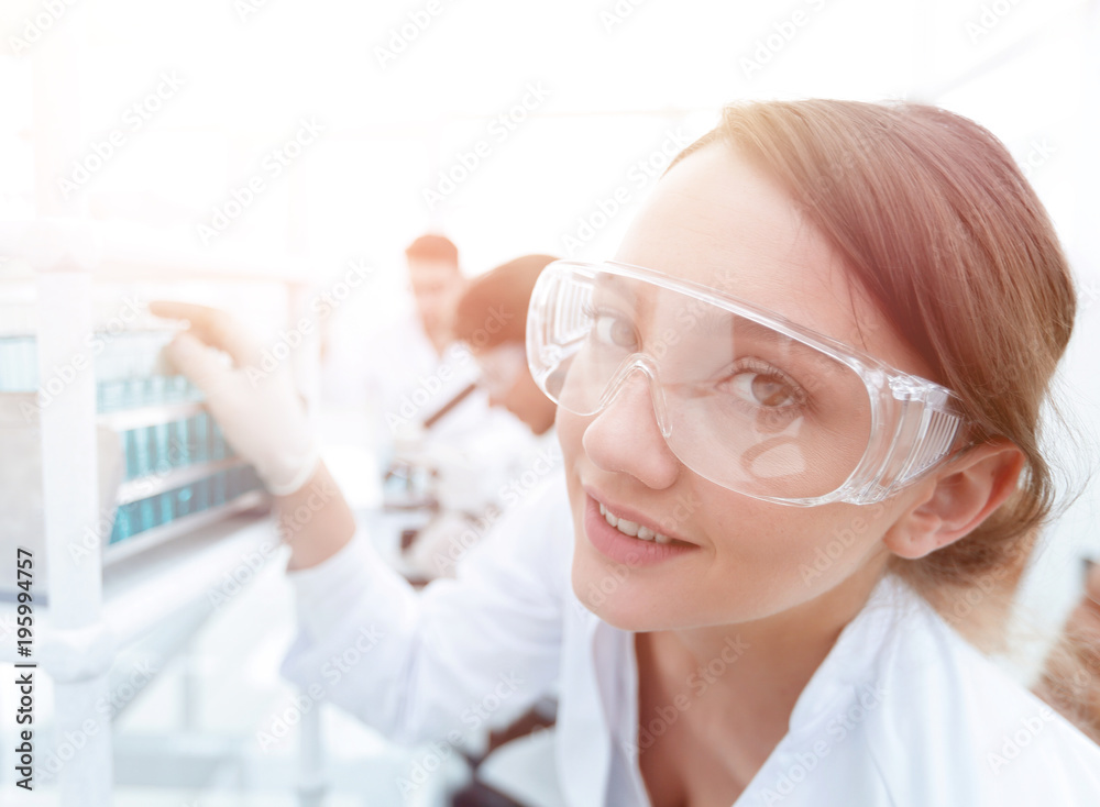 Young woman scientist in protective glasses holding test tubes Young woman scientist in protective glasses holding test tubes