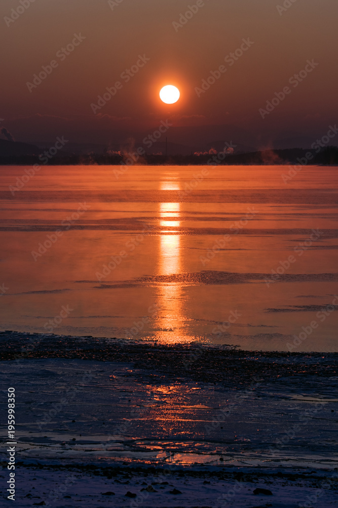 Colorful sunrise over lake and chimneys