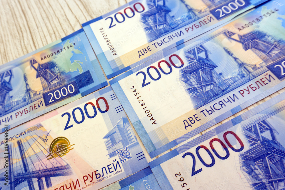 Man's hand holds a new Russian banknote of two thousand rubles against the background of green cash machine . Man's hand holds a new Russian banknote of two thousand rubles against the background of green cash machine .