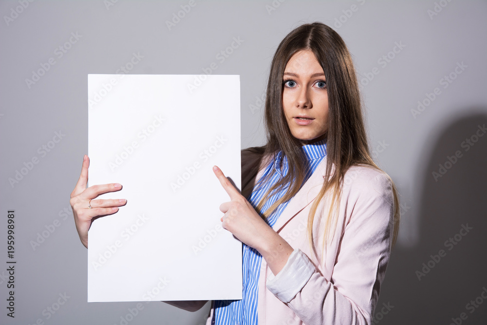 Young beautiful woman pointing at a blank sheet Young beautiful woman pointing at a blank sheet
