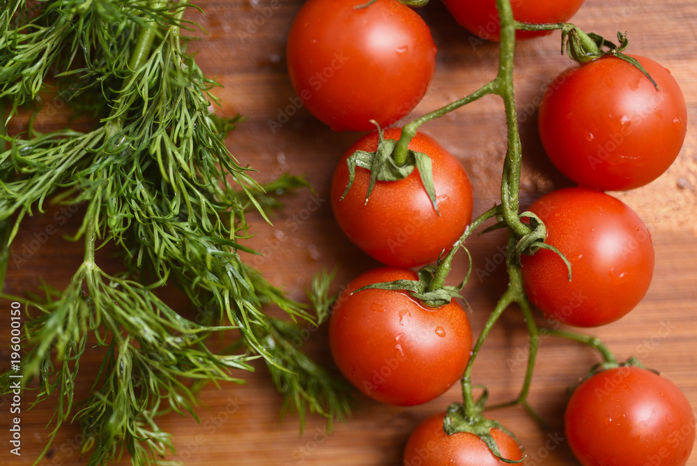 Cherry tomatos and heap of dill on wooden surface Cherry tomatos and heap of dill on wooden surface