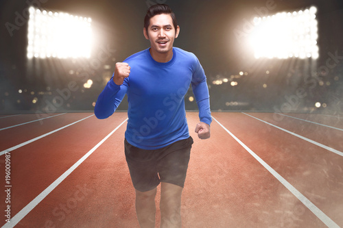 Spiritful asian athlete running on the track