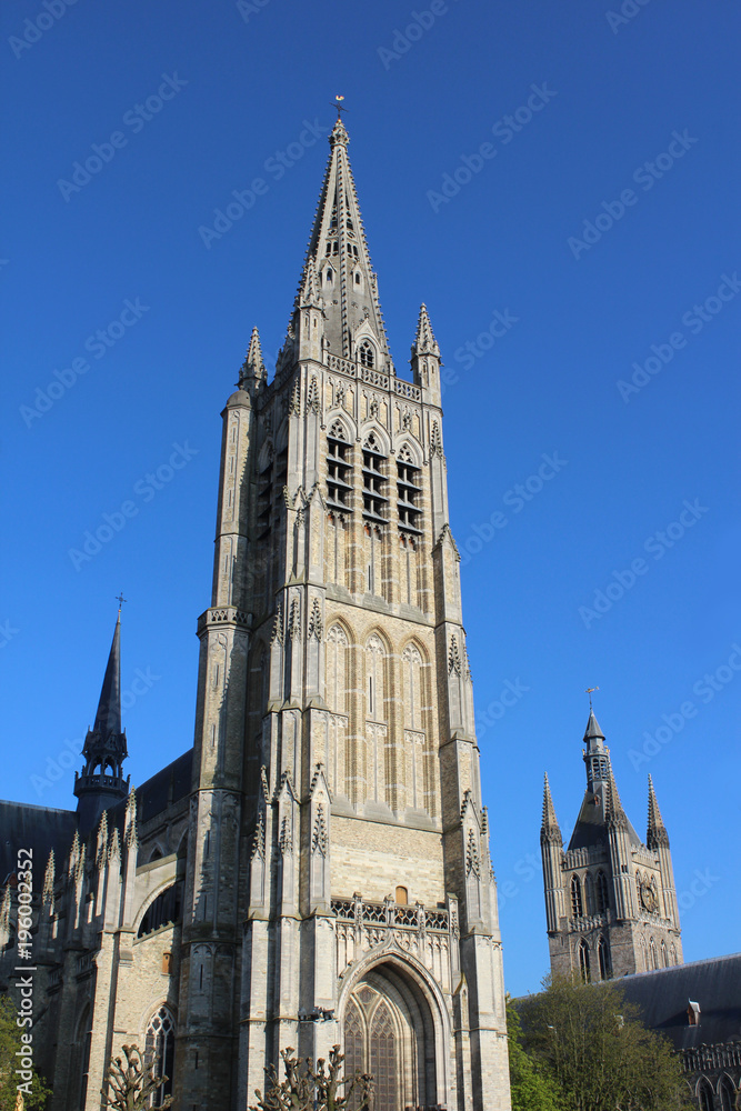 Exterior view of the beautiful St. Maartens Cathedral, in Ieper, Belgium, lit by the evening sun against a background of blue sky.