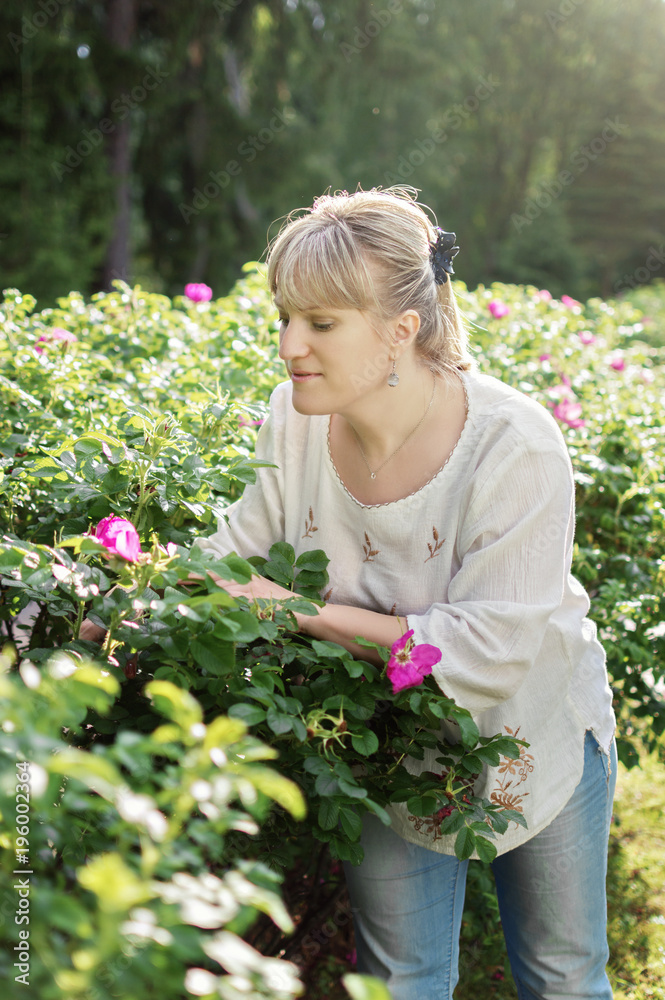 blond woman strolling in a park among flowers blond woman strolling in a park among flowers
