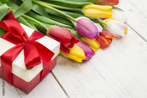 bouquet of tulips with a gift on rustic wooden board