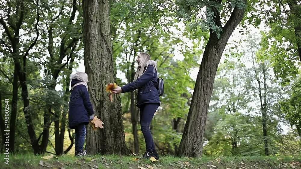 Mother and daughter throw up yellow leaves in autumn park. Mother and daughter throw up yellow leaves in autumn park.