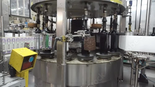 Machine applying excise stamps for wine products at a distillery. Bottling and sealing conveyor line at winery factory. 