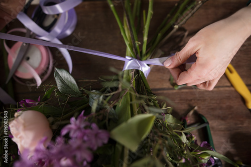 closeup image of strait-lacing ribbon on bouquet, florist's table