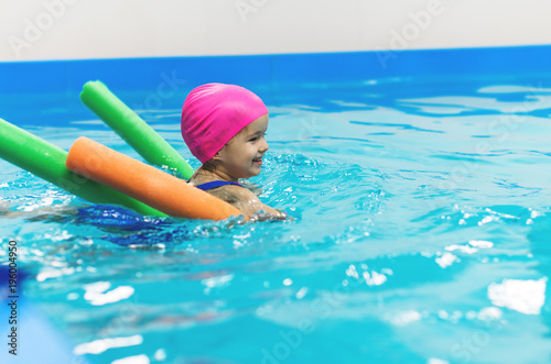A little girl of European appearance floating in the pool on inflatable toy