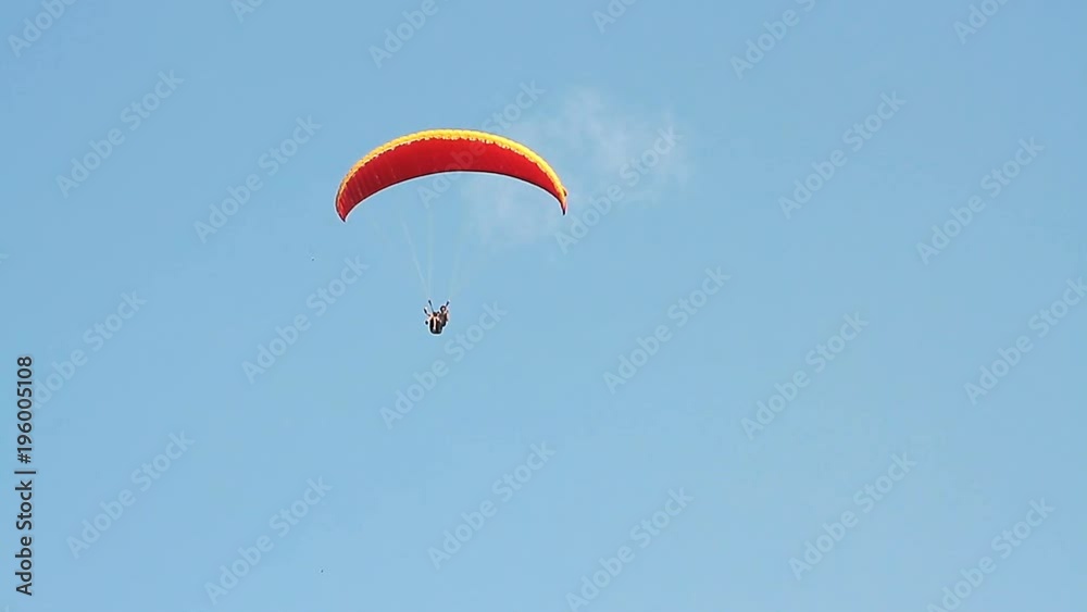 Paragliding over the mountains against clear blue sky Paragliding over the mountains against clear blue sky