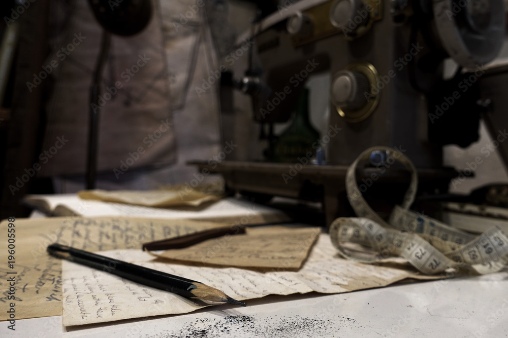 Designer pencil on ideas paper with dark background of sewing machine in tailor shop Designer pencil on ideas paper with dark background of sewing machine in tailor shop