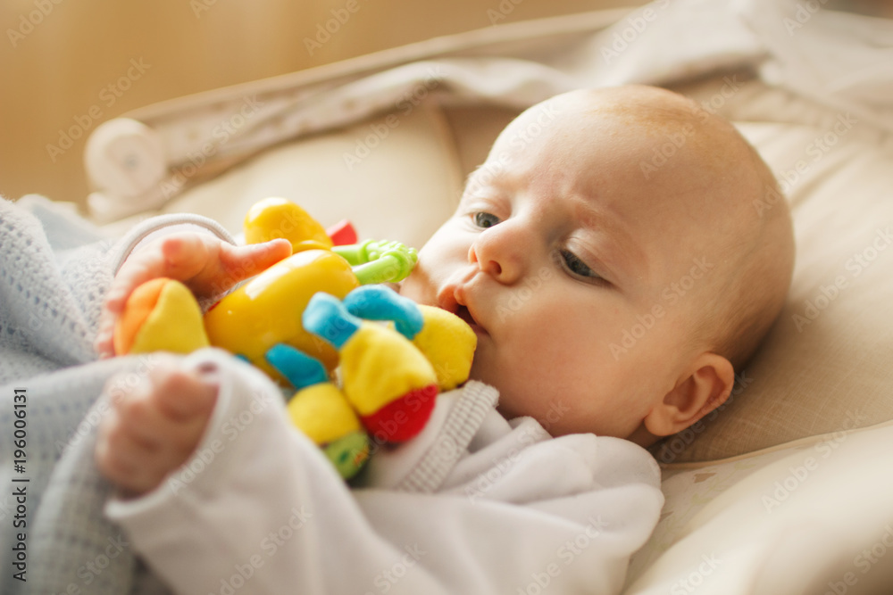 a small child lies and plays with a toy. baby with a toy in his mouth a small child lies and plays with a toy. baby with a toy in his mouth