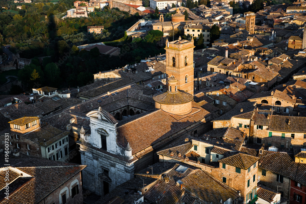 Picturesque aerial view of Chiesa di San Martino from Torre del Mangia tower at sunset, Siena, Tuscany, Italy. Scenic travel destination postcard.