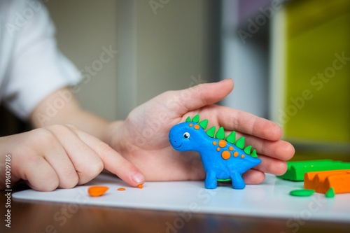 Fototapeta Naklejka Na Ścianę i Meble -  Creative kid molding at home. child play with plasticine. child sculpts a dinosaur