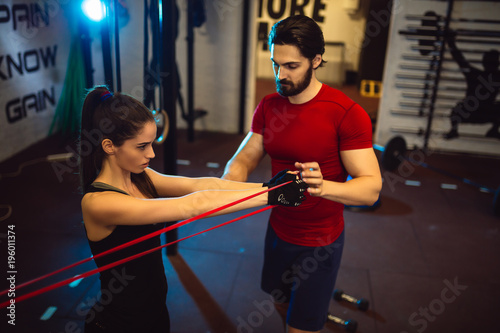 Young girl exercising at the gym with a male personal trainer.