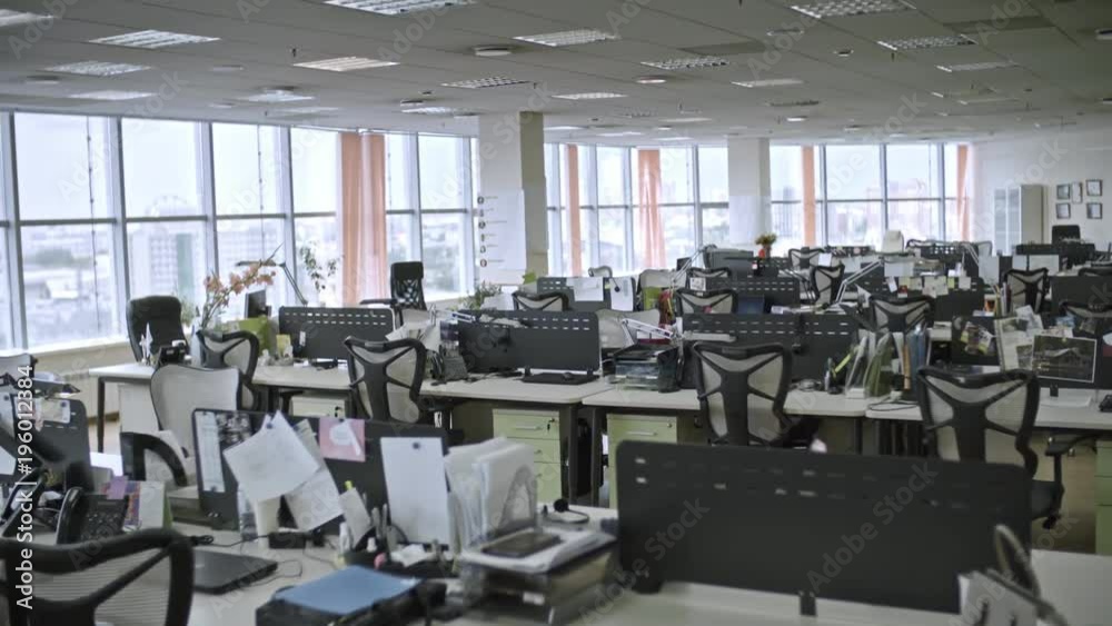 Dolly shot of big empty office with large windows and workers’ things on tables, shot in daytime Dolly shot of big empty office with large windows and workers’ things on tables, shot in daytime