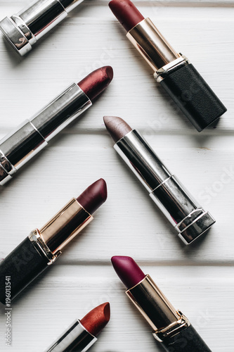 Lipsticks of different colors on wooden background