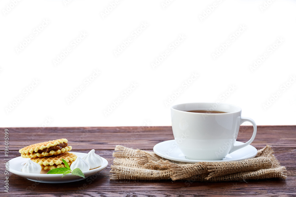 Afternoon tea and waffles on wooden table over white background, close-up, selective focus Afternoon tea and waffles on wooden table over white background, close-up, selective focus