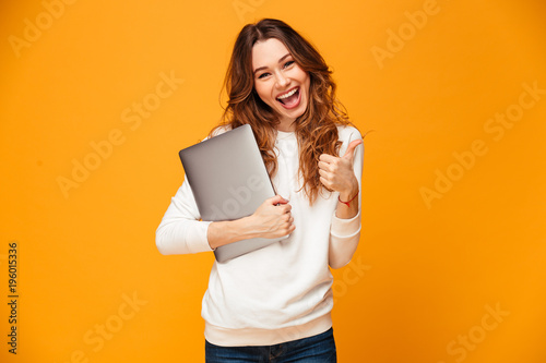 Happy brunette woman in sweater holding laptop computer