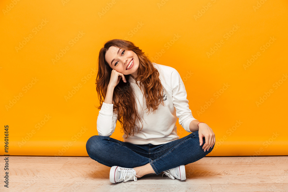 Pleased brunette woman in sweater sitting on the floor Pleased brunette woman in sweater sitting on the floor