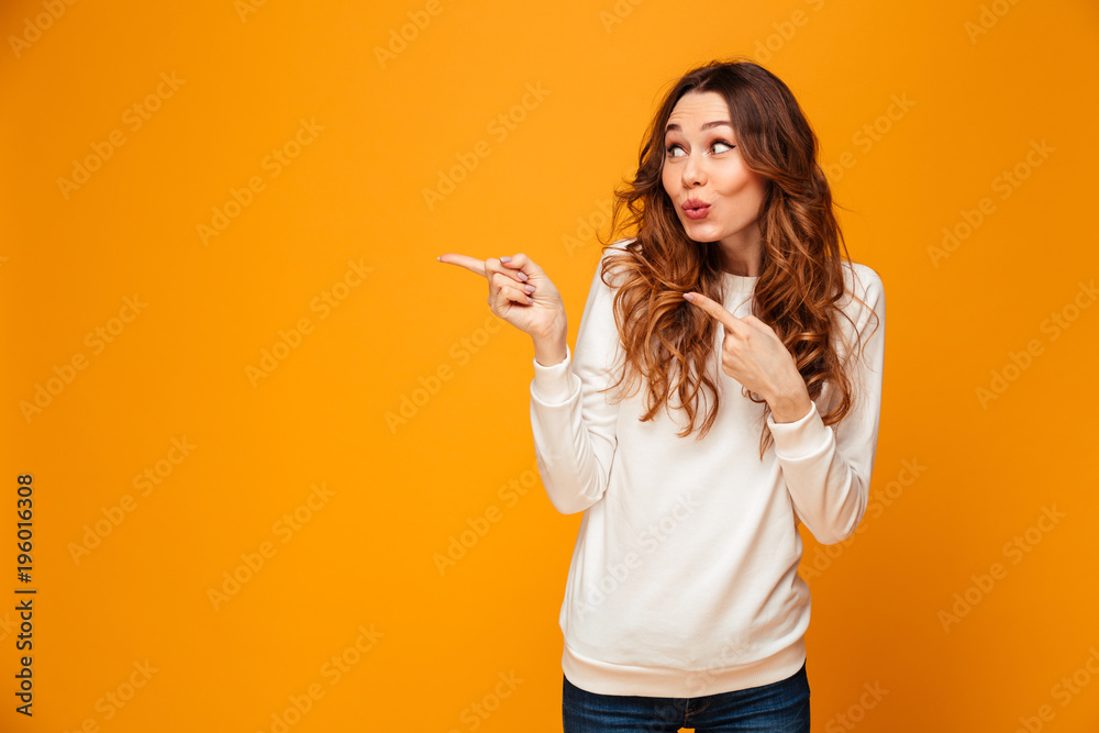 Funny brunette woman in sweater looking and pointing away - obrazy, fototapety, plakaty 