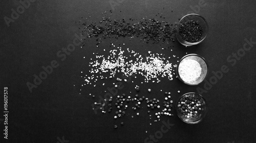 Glass with assorted peppercorns on black background, black and white