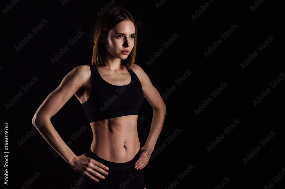 Sporty muscular female doing workout with dumbbells isolated on black background. Athletic young woman do a fitness workout with weights. Sporty muscular female doing workout with dumbbells isolated on black background. Athletic young woman do a fitness workout with weights.