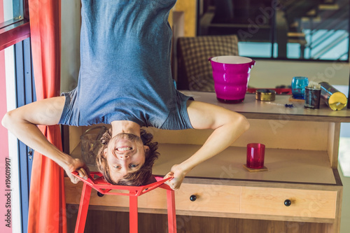 A man stands on his hands upside down in the kitchen photo