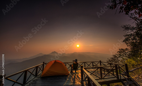 In the morning. Tourists watch the sunrise on a wooden balcony.
