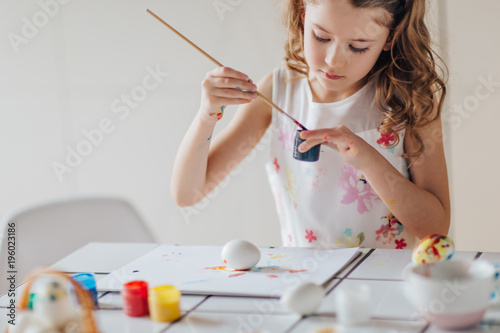 Close view of little girl painting easter eggs 