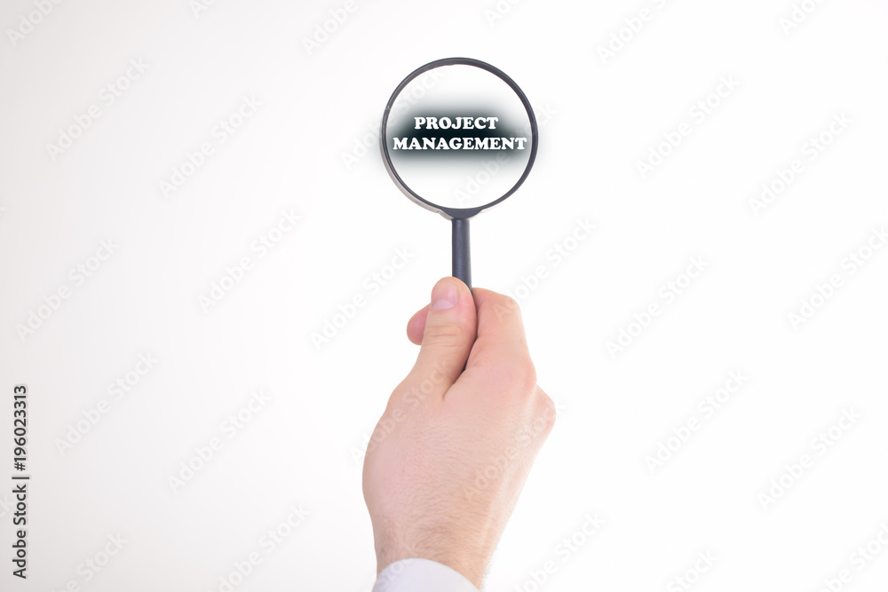 Businessman looking at a magnifying glass word:PROJECT MANAGEMENT