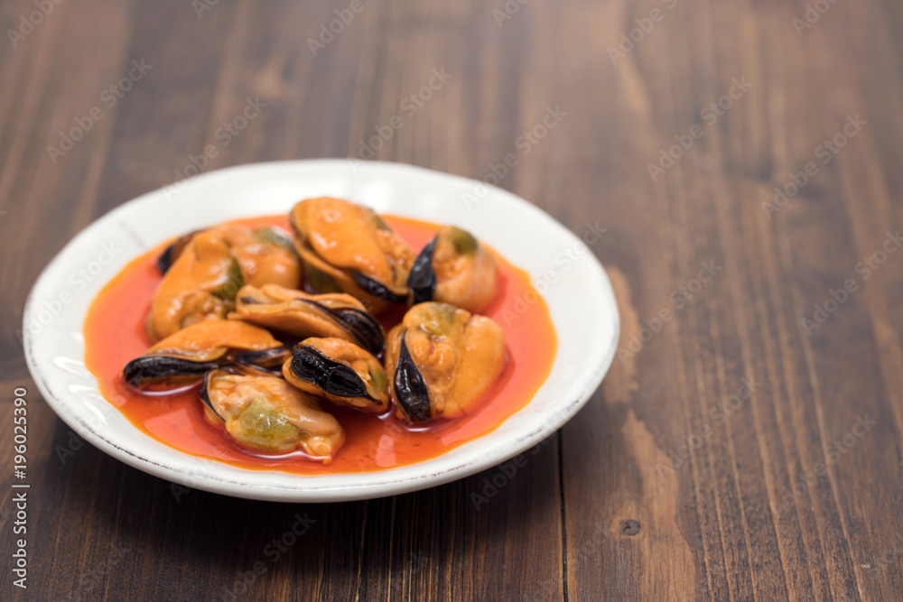 mussels in sauce on white dish on wooden background