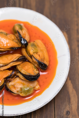 mussels in sauce on white dish on wooden background