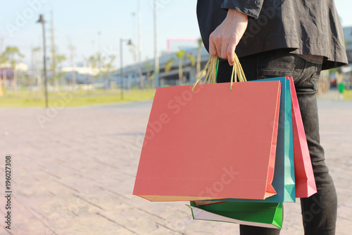 Closeup of man holding shopping bags with standing at the car parking lot