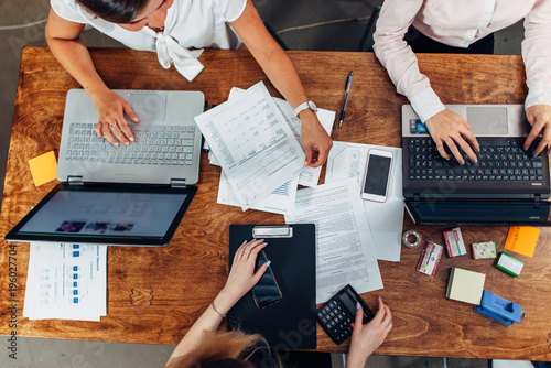 Foto Top view of three women working with documents using laptops sitting at desk
