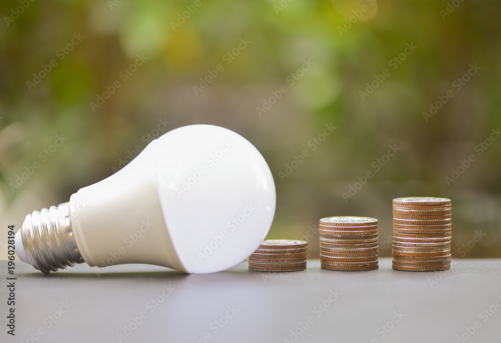 LED Bulb and Coin stack with green glass background for saving concept LED Bulb and Coin stack with green glass background for saving concept