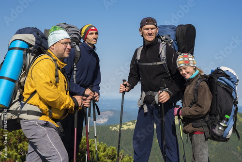 Hikers, company of friends with backpacks are standing in the mountains
