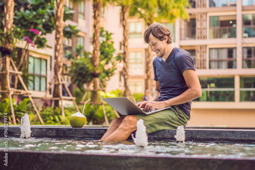 Young freelancer working on vacation next to the swimming pool