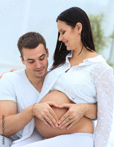 closeup .husband and pregnant wife putting their hands on her tummy.