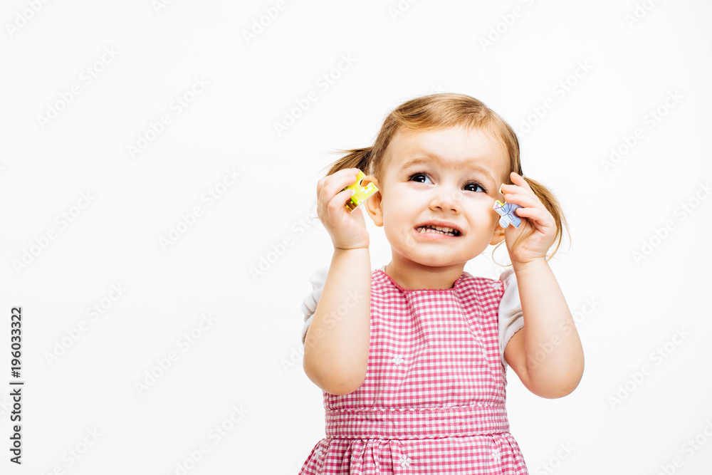 Preschool toddler girl having difficulty with puzzles she's holding Preschool toddler girl having difficulty with puzzles she's holding