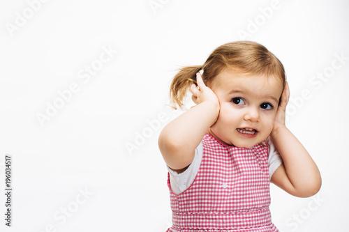 Preschool toddler girl with ponytails and holding her head isolated on white background
