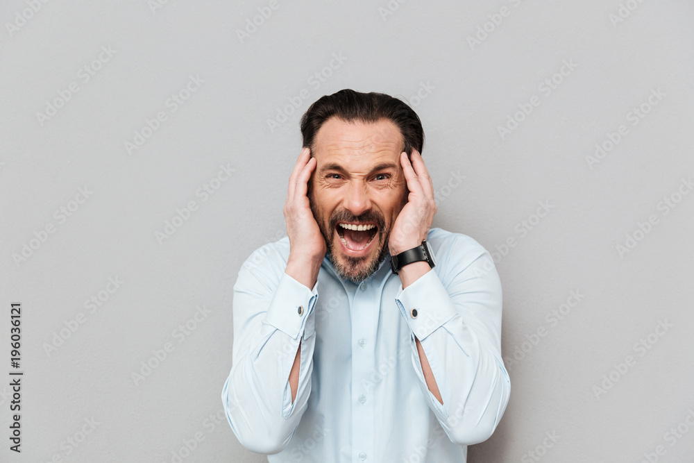 Portrait of an angry mature man dressed in shirt screaming Portrait of an angry mature man dressed in shirt screaming