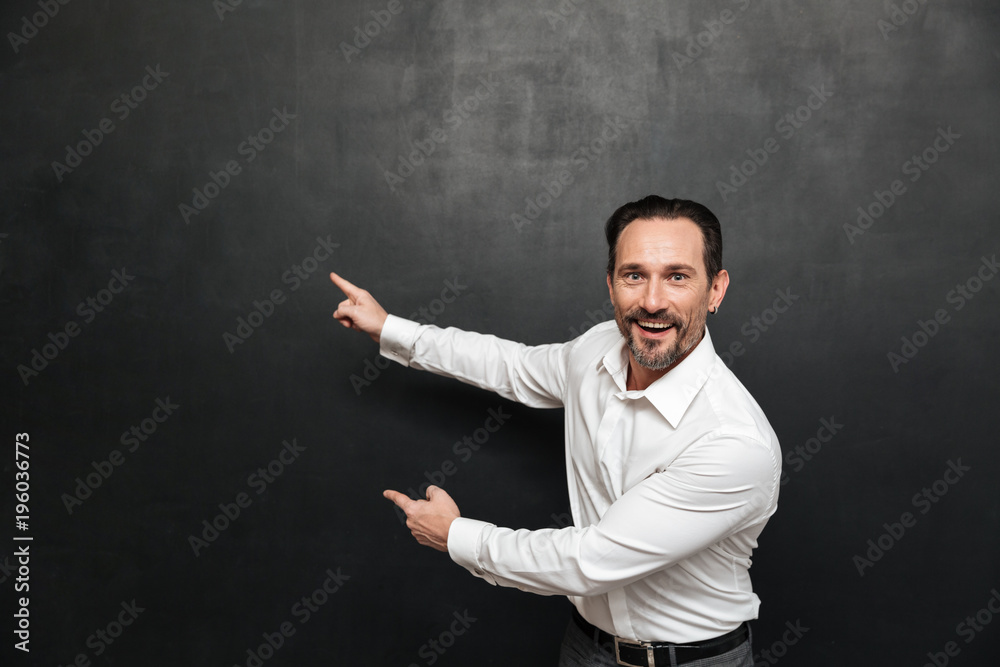 Portrait of an excited mature man dressed in shirt pointing Portrait of an excited mature man dressed in shirt pointing