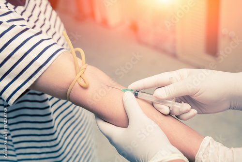 Close up nurse pricking needle syringe in the arm patient drawing blood sample for blood test