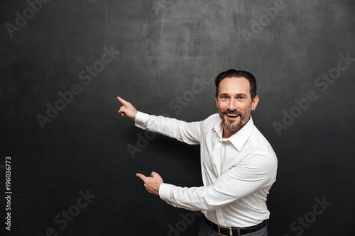 Portrait of an excited mature man dressed in shirt pointing © Drobot Dean